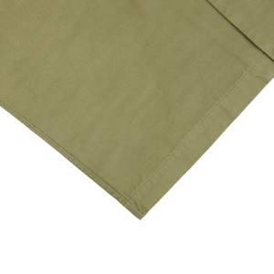 A Grass Green Greto Cotton Overshirt folded on top of a white surface.