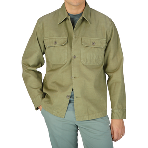 A man wearing a Grass Green Greto Cotton Overshirt and pants by Tela Genova.