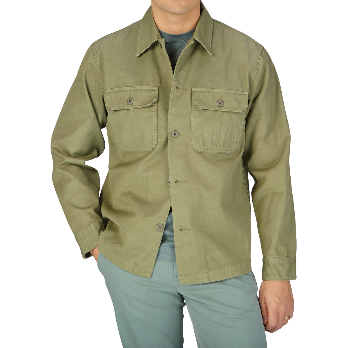 A man wearing a Grass Green Greto Cotton Overshirt and pants by Tela Genova.