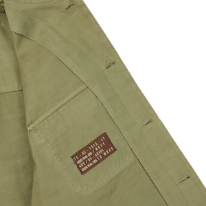 The pocket of a Grass Green Greto Cotton Overshirt with a brown label on it by Tela Genova.