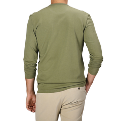 A person in a Tela Genova Grass Green Heavy Organic Cotton LS T-Shirt and beige pants stands with their back to the camera.