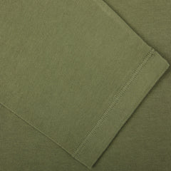 Close-up of a Grass Green Heavy Organic Cotton LS T-Shirt fabric by Tela Genova, highlighting the sleeve cuff and stitching detail. Crafted from organic cotton, this piece exemplifies the quality and precision you'd expect from a heritage clothing line.