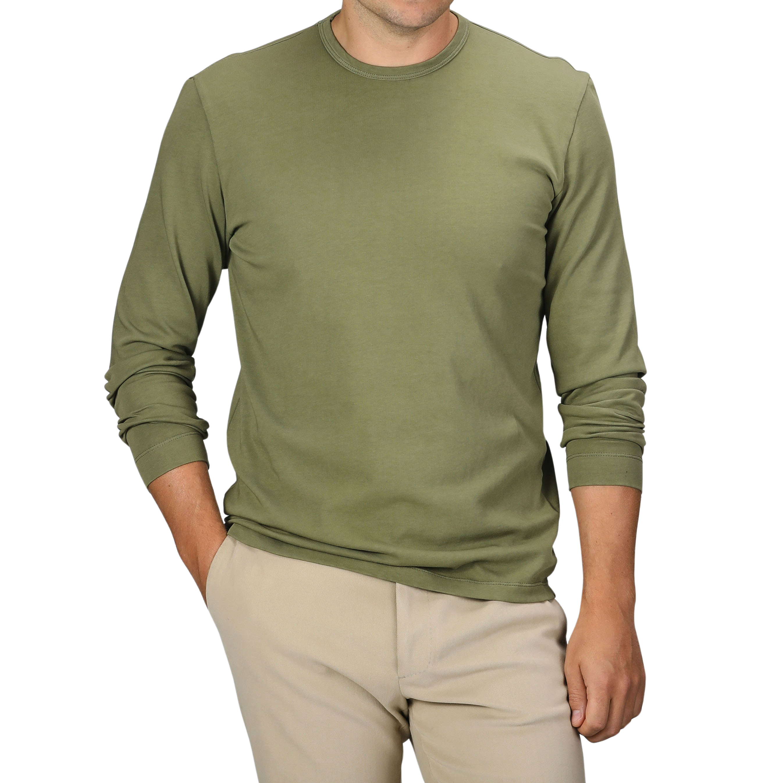 A person is standing with one hand in their pocket, dressed in a Tela Genova Grass Green Heavy Organic Cotton LS T-Shirt and beige pants. Their face is not visible.