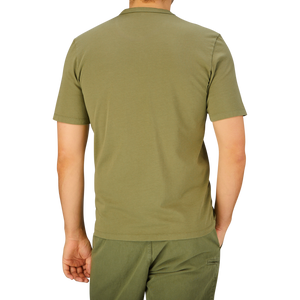 Man standing with his back facing the camera, wearing a plain olive green Tela Genova Green Heavy Organic Cotton T-Shirt and matching pants.