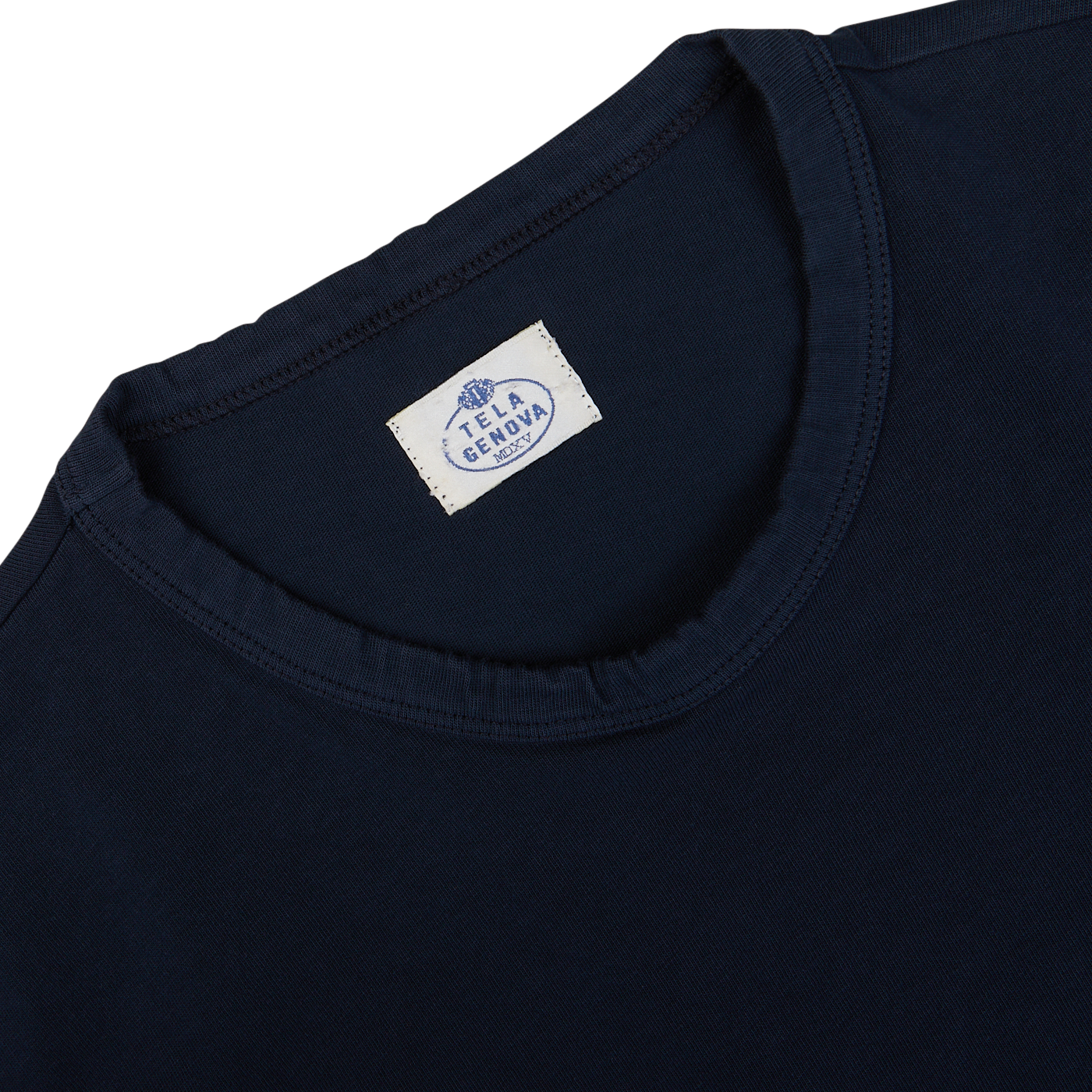 Close-up of the Navy Blue Heavy Organic Cotton LS T-Shirt from Tela Genova, showcasing a long-sleeve design with a white fabric tag inside the neckline bearing the brand name, epitomizing heritage clothing at its finest.