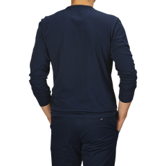 A person wearing a Tela Genova Navy Blue Heavy Organic Cotton LS T-Shirt and matching navy pants made from organic cotton stands with their back to the camera against a plain background.