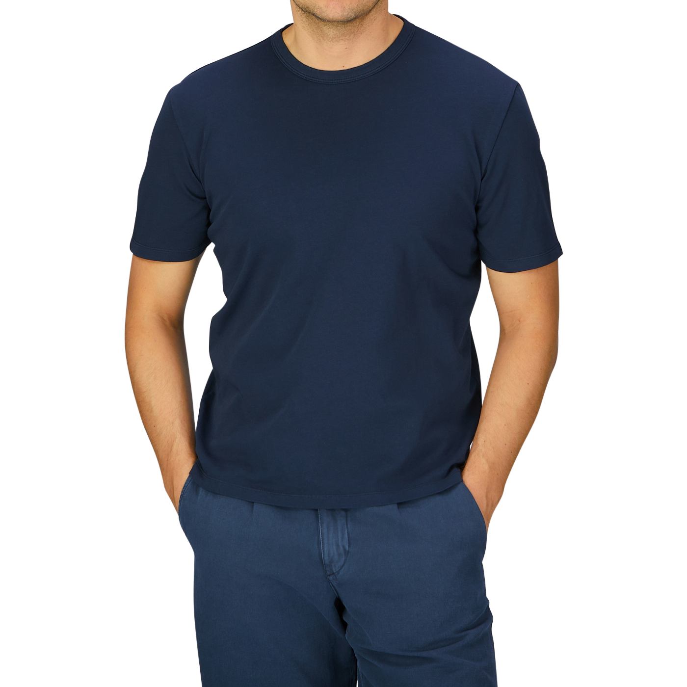 A man wearing a Navy Blue Heavy Organic Cotton T-Shirt by the Italian brand Tela Genova and blue pants standing against a grey background.
