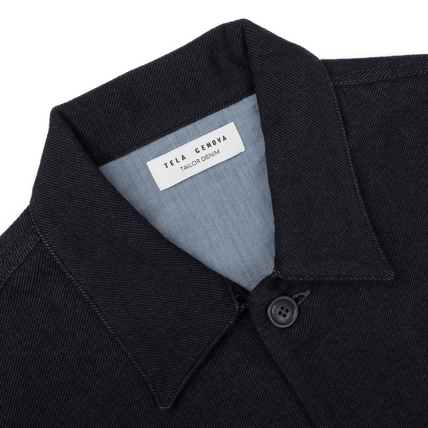 Close-up of a dark denim shirt featuring a label inside the collar that reads "Tela Genova," providing a sophisticated casual vibe similar to the Navy Blue Wool Cotton Greto Overshirt.