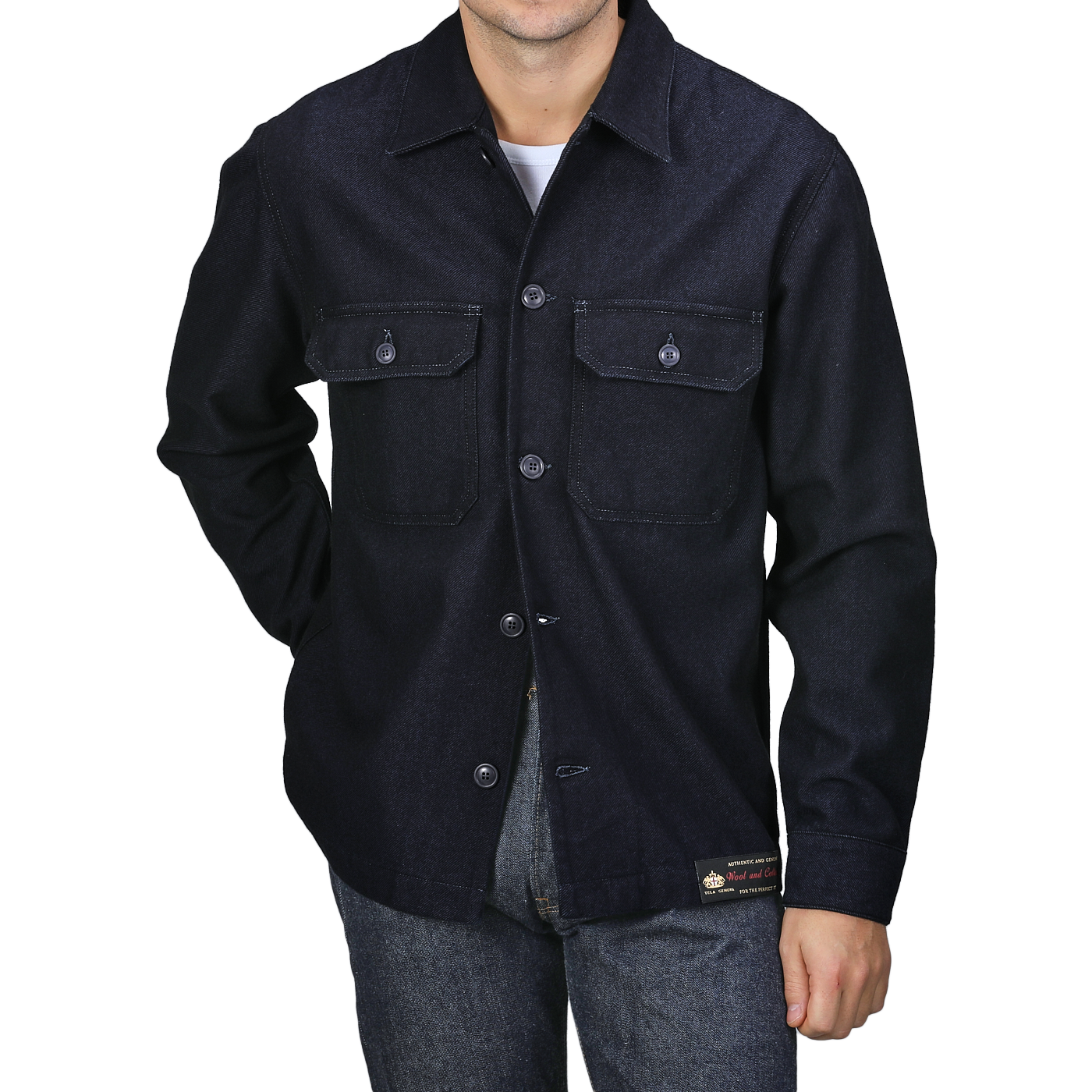 Dressed in the Tela Genova Navy Blue Wool Cotton Greto Overshirt and jeans, a person effortlessly exudes a sophisticated casual look, standing against a plain background.