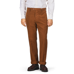 A person wearing Tela Genova's Tobacco Brown Cotton Moleskin Berardo Trousers, paired with a white shirt and brown shoes, stands against a plain background.