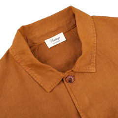 The Tobacco Pure Linen Camillo Jacket from Tela Genova features a brown, button-up design with a collar and a single visible button, ideal for casual wear. Inside, the "Heritage Flaxseed" label guarantees quality pure linen.