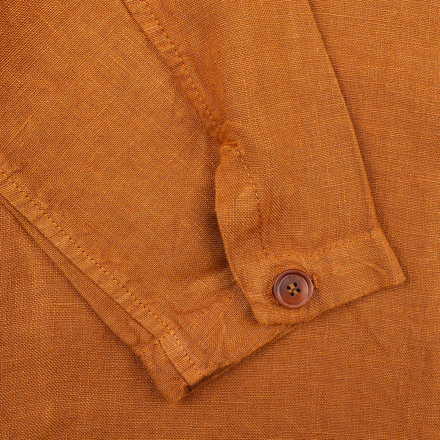 Close-up of Tela Genova's Tobacco Pure Linen Camillo Jacket, featuring a buttoned cuff. The textured, slightly wrinkled material enhances its casual look.