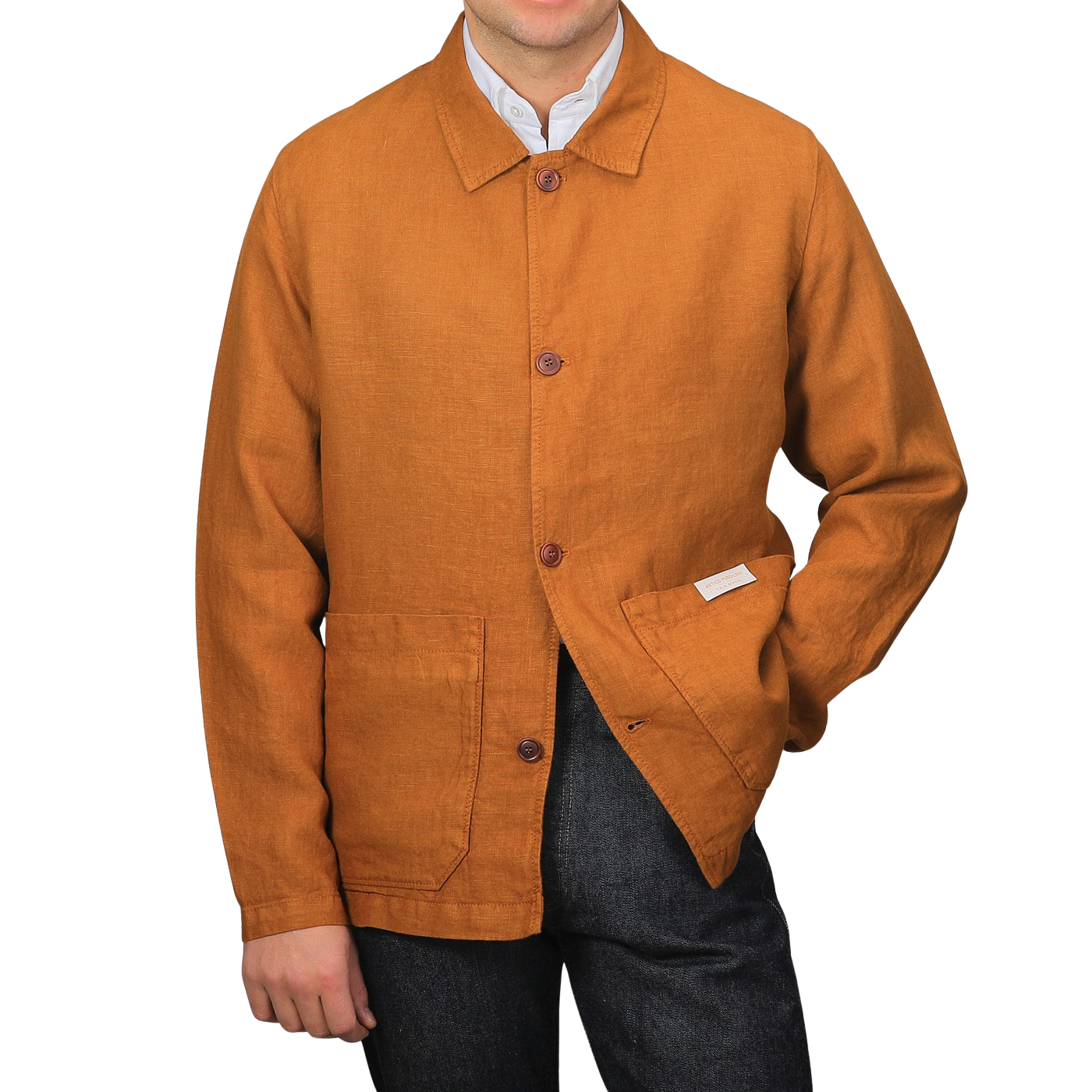 A person in a Tela Genova Tobacco Pure Linen Camillo Jacket featuring two front pockets and dark pants stands casually against a plain background.