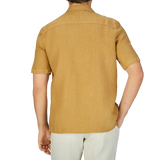 The back view of a man wearing a Tobacco Renato Linen Camp Collar Shirt with a summer feel by Tela Genova.