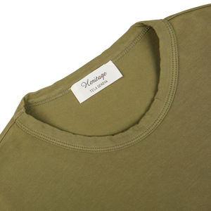 Close-up of a Tela Genova green Heavy Organic Cotton T-Shirt's collar with a white clothing label.
