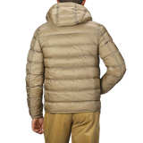 A person wearing a Ten C Beige Nylon Down Padded Liner Hood Jacket, viewed from the back. This technical outerwear features premium goose down insulation, ensuring warmth and comfort in colder conditions.