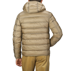 A person wearing a Ten C Beige Nylon Down Padded Liner Hood Jacket, viewed from the back. This technical outerwear features premium goose down insulation, ensuring warmth and comfort in colder conditions.