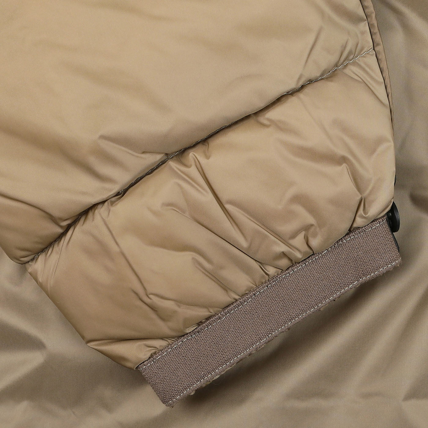 Close-up of the Beige Nylon Down Padded Liner Hood Jacket sleeve by Ten C, featuring an elastic cuff and highlighting the technical outer design of this sleek goose down liner jacket.