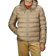 A person wearing a Ten C Beige Nylon Down Padded Liner Hood Jacket with a visible front zipper and their hands in the pockets. The jacket is paired with mustard-colored pants and a burnt orange sweater underneath.