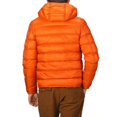 A person wearing the Ten C Orange Nylon Down Padded Liner Hood Jacket and brown pants is shown from the back, the technical outer nylon and goose down padding providing both warmth and durability.