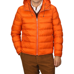 A person wearing an Orange Nylon Down Padded Liner Hood Jacket by Ten C over a white collared shirt and maroon sweater, paired with brown pants.