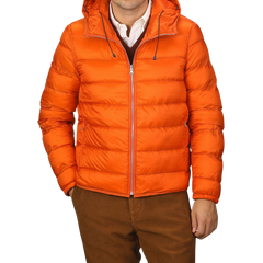 A person wearing an Orange Nylon Down Padded Liner Hood Jacket by Ten C over a white collared shirt and maroon sweater, paired with brown pants.