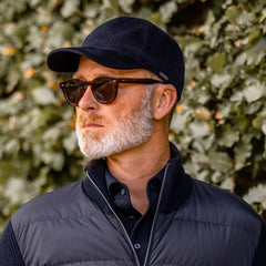 A man wearing a black vest and sunglasses, dressed in a three-piece suit, is sporting the Donegal Havana Frame with Bottle Green Lenses from The Bespoke Dudes.