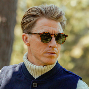 A man wearing The Bespoke Dudes sunglasses with Lapel Amber Tortoise Green Lenses 49mm and an amber tortoise-shell frame, handmade in Italy.