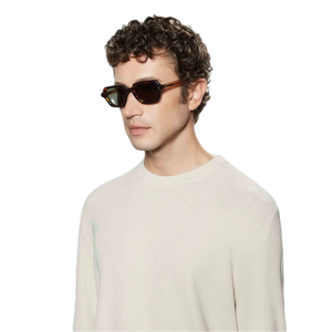 A young man with curly hair wearing a white sweater and square-shaped sunglasses, posed against a black background wearing The Bespoke Dudes Oak Eco Bicolor Bottle Green Lenses 49mm.