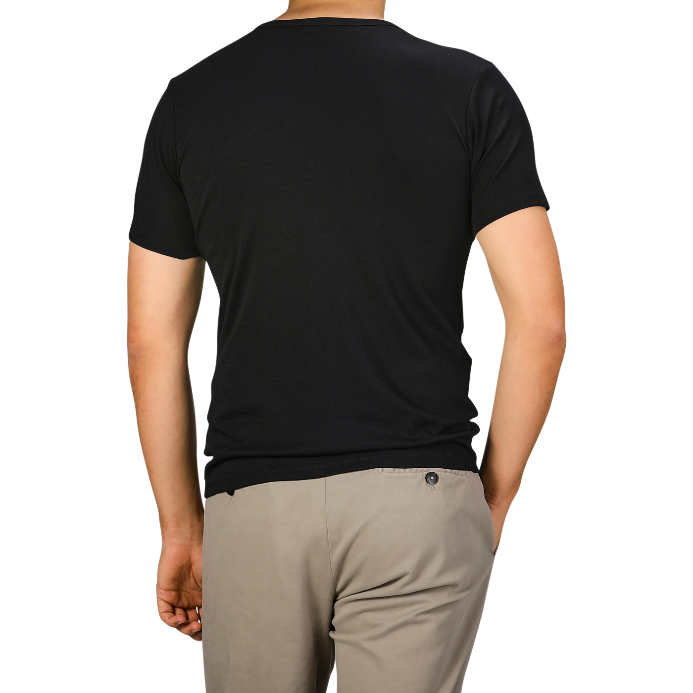 Rear view of a person standing, wearing The White Briefs' Black Pima Cotton Earth T-Shirt made from organic pima cotton and beige pants against a plain background.