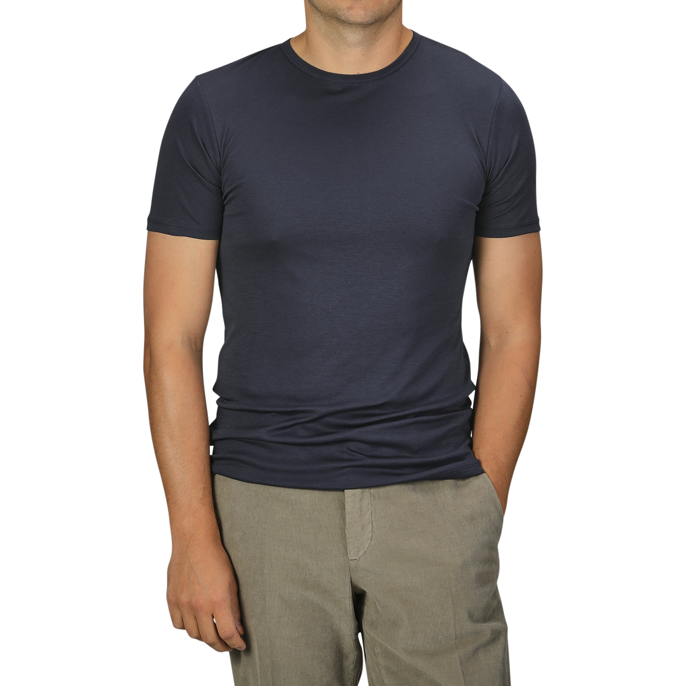 A man in a Parisian Night Pima Cotton Earth T-Shirt by The White Briefs and beige pants stands with his hands partially in his pockets against a gray background.