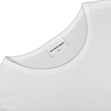 Close-up of a slim fit, white crewneck T-shirt neckline featuring a "The White Briefs Medium" label, made from organic pima cotton, known as the White Pima Cotton Earth T-Shirt.