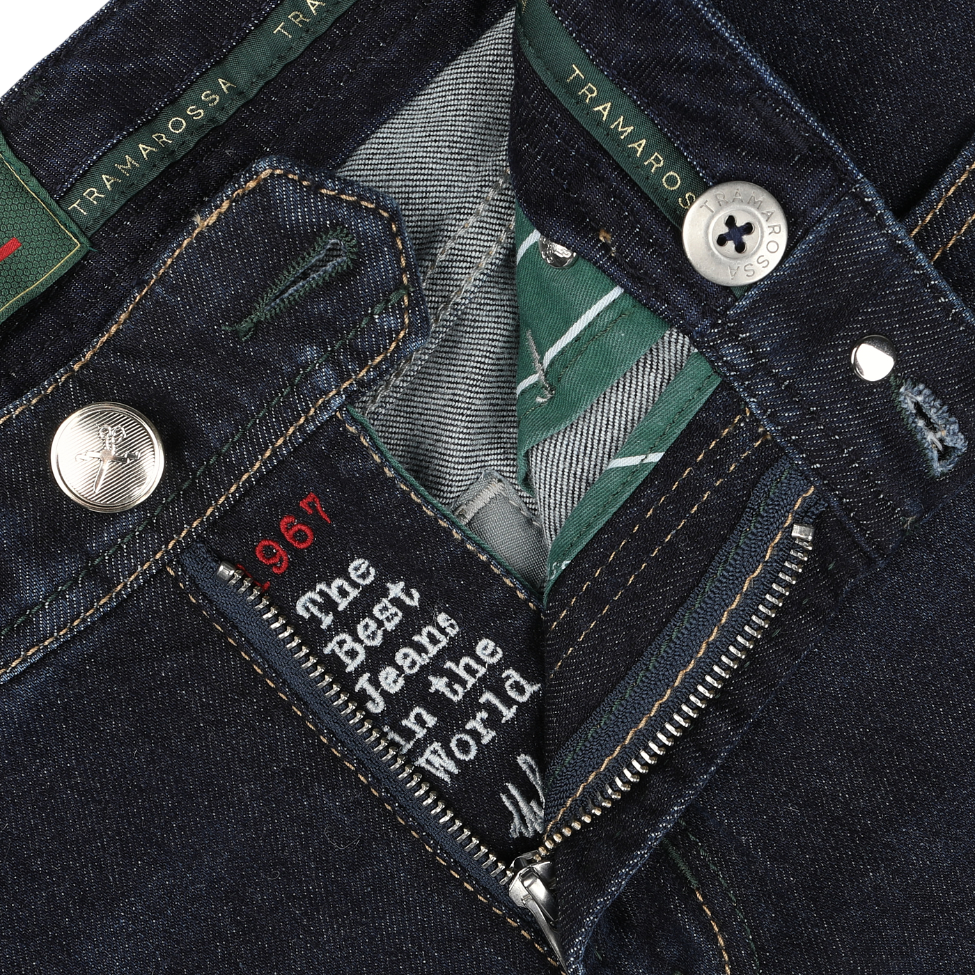 Close-up view of the open zipper fly of a pair of dark blue cotton cashmere Michelangelo jeans, revealing a label with text and button details marked with the brand name "Tramarossa," showcasing comfort stretch denim for ease and customization with initials.