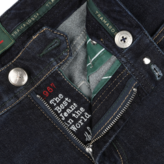 Close-up view of the open zipper fly of a pair of dark blue cotton cashmere Michelangelo jeans, revealing a label with text and button details marked with the brand name "Tramarossa," showcasing comfort stretch denim for ease and customization with initials.