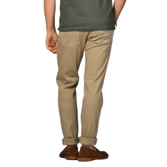 Rear view of a person wearing a dark green shirt, Tramarossa Desert Beige Super Stretch Michelangelo Jeans, and brown shoes, standing against a neutral background.