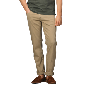 Person wearing a dark green shirt, Tramarossa Desert Beige Super Stretch Michelangelo Jeans, and brown shoes, standing with one hand in pocket.