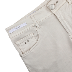 Close-up of Tramarossa Off White Super Stretch Michelangelo Jeans with a button closure, "R-ELAX" label on the waistband, and "IB" monogram on the front pocket. Crafted from comfort stretch denim for unmatched comfort and style.