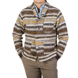 A man wearing a Universal Works Brown Fair Isle Wool New York Button Cardigan, crafted from boiled merino wool mix, paired with pants.