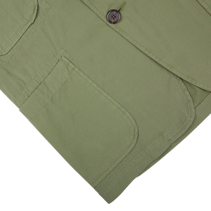 Birch green Universal Works trousers with a buttoned pocket detail.