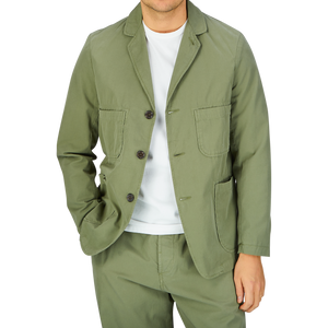 Man wearing a green Universal Works Birch Green Cotton Summer Canvas 5-Pocket Jacket over a white t-shirt.