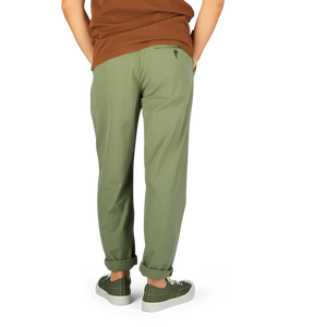 Person wearing Universal Works Birch Green Cotton Summer Canvas Military Chinos and two-tone sneakers standing against a neutral background.