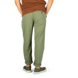 Person wearing Universal Works Birch Green Cotton Summer Canvas Military Chinos and two-tone sneakers standing against a neutral background.