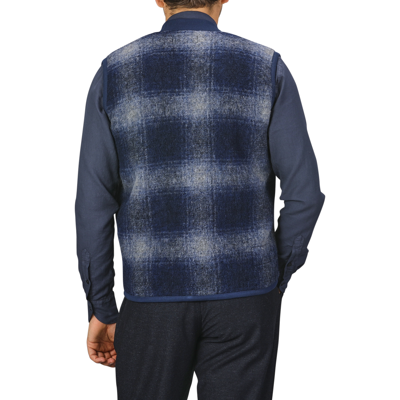 Back view of a person wearing a Blue-Grey Fresco Fleece Zip Waistcoat by Universal Works over a dark blue shirt and dark pants, standing against a plain light gray background.