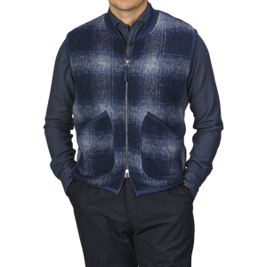 A person wearing a navy blue shirt and a Blue-Grey Fresco Fleece Zip Waistcoat by Universal Works, which serves as a perfect layering piece with two front pockets, stands against a plain background.