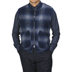 A person wearing a navy blue shirt and a Blue-Grey Fresco Fleece Zip Waistcoat by Universal Works, which serves as a perfect layering piece with two front pockets, stands against a plain background.