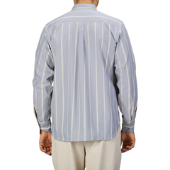 A person wearing a Blue Sydney Striped Cotton Lazy Day Shirt by Universal Works and beige pants, seen from the back.