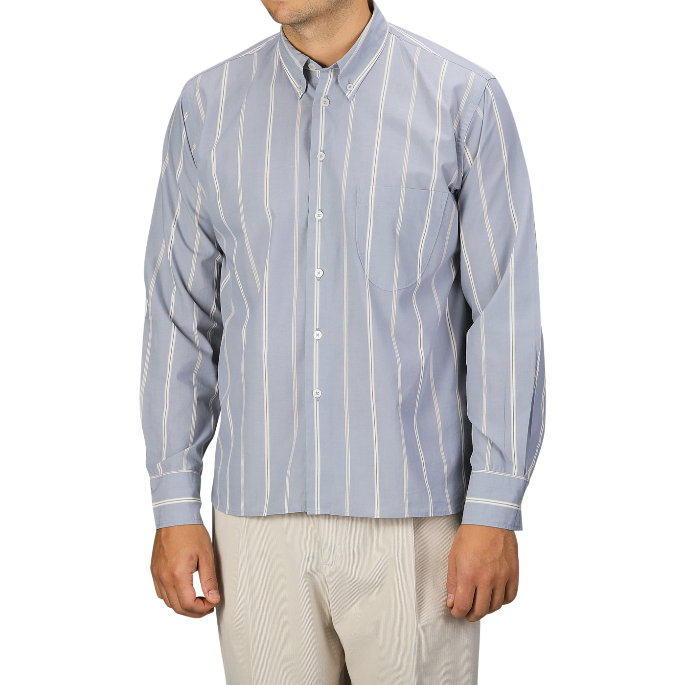 A man wearing a Universal Works Blue Sydney Striped Cotton Lazy Day Shirt with beige pants stands against a plain background. His face is not visible.