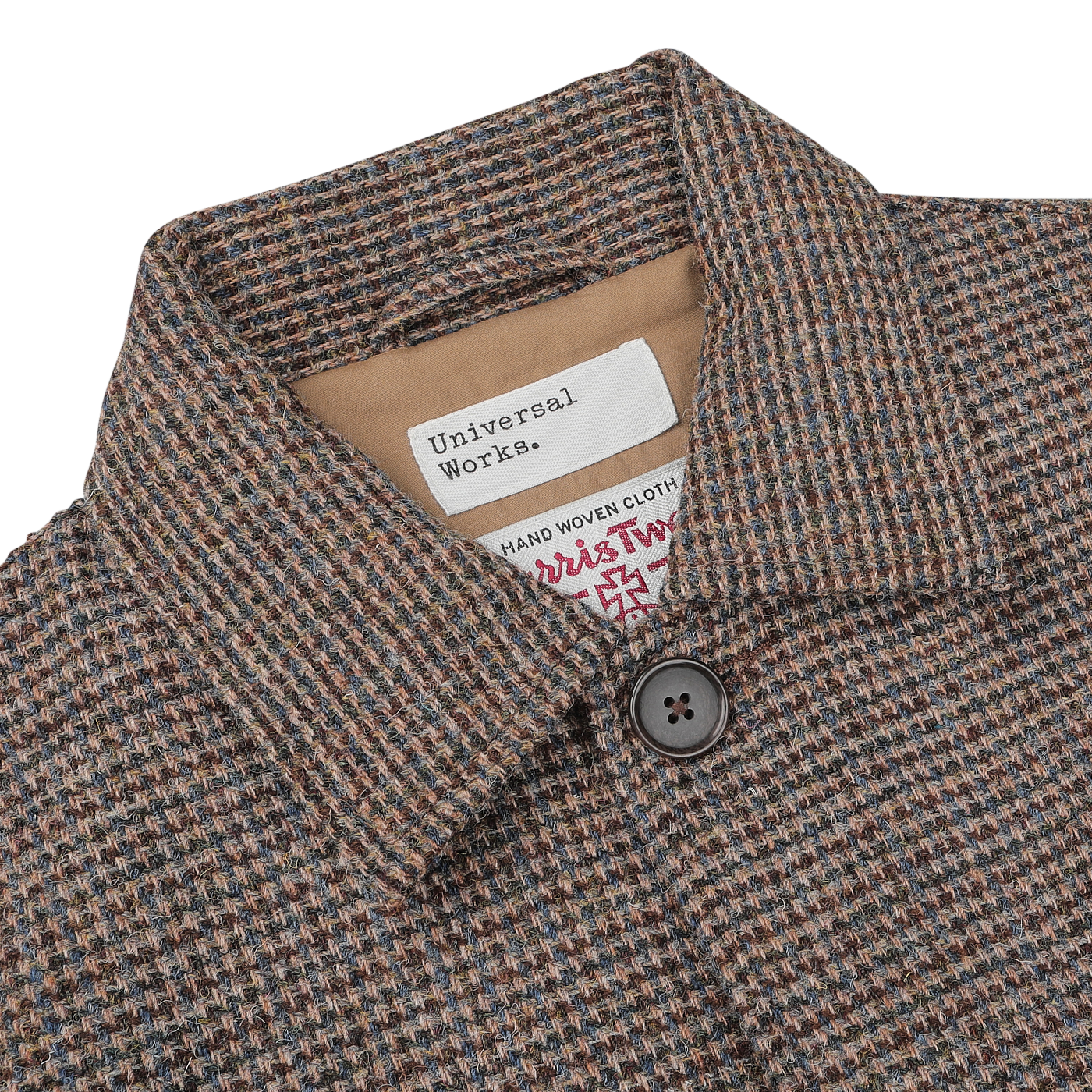 Close-up of a checked Brown Melange Harris Tweed Bakers C Jacket with a buttoned collar, displaying the Universal Works and Harris Tweed labels, indicating it is made from hand-woven cloth.