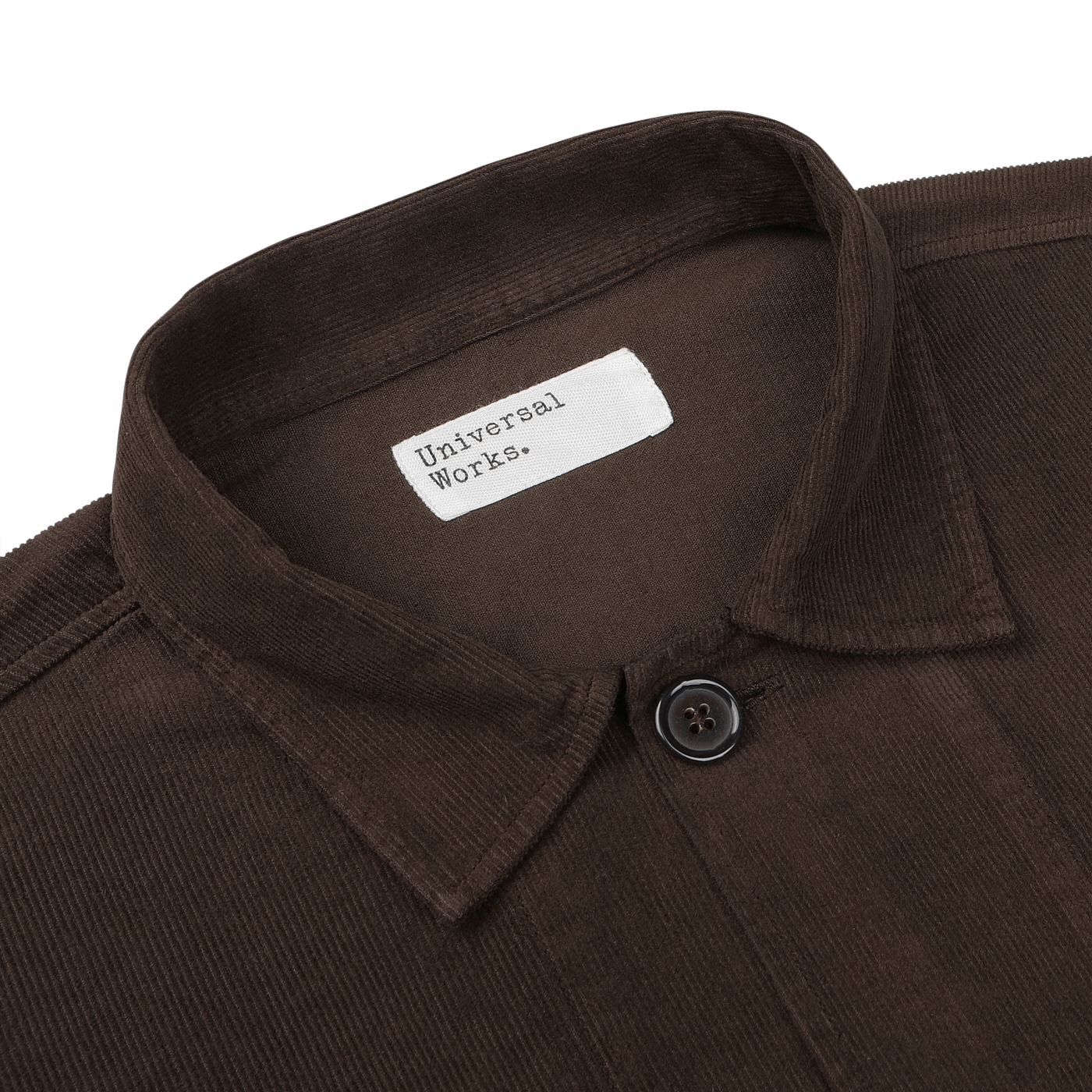 A close-up image of a Dark Brown Fine Corduroy Bakers Overshirt by Universal Works, showcasing a single button and the white label with the brand name.