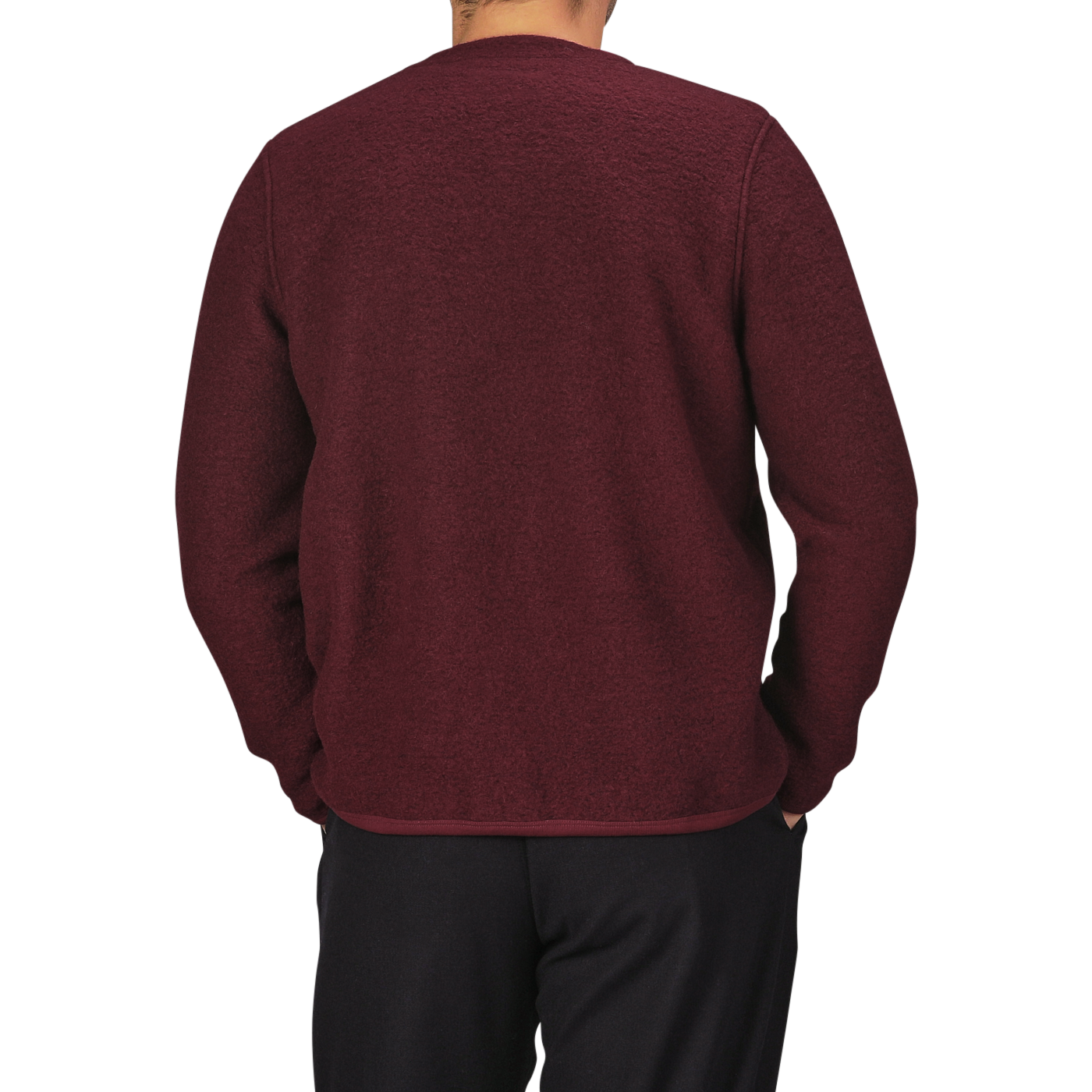 A person wearing the Deep Red Wool Fleece Cardigan from Universal Works and black pants is shown from the back. The background is plain and light-colored.